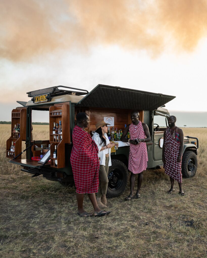 Twinkle Star Tours guides sharing a drink with a tourist at Mara Bush Camp