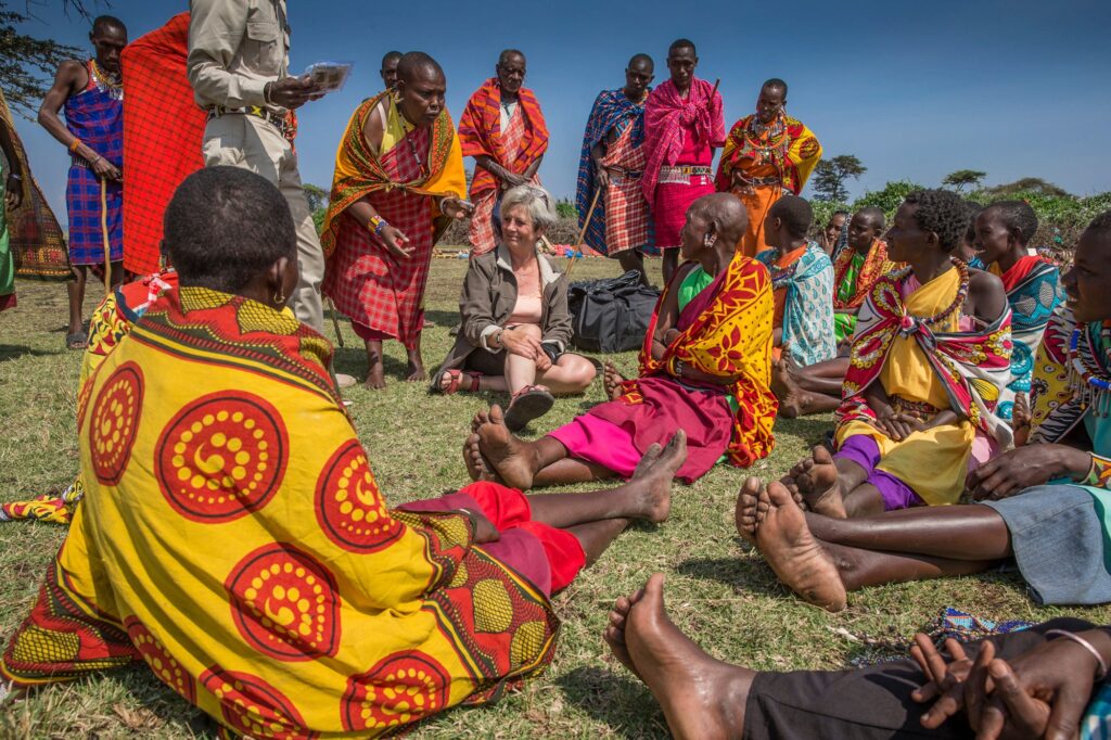 a tourists interacting with maasai women during a maasai village tour while relaxing at Karen Blixen Luxury Safari Camp Masai Mara